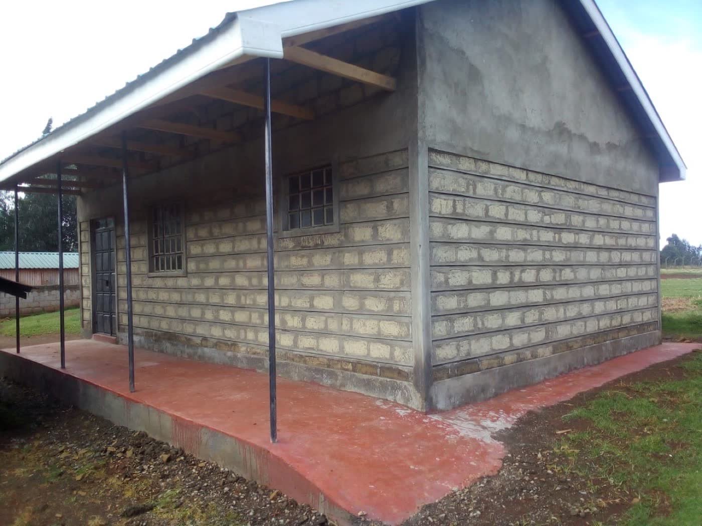 The new stone kitchen building seen from its verandah side, with steel windows and a red-finished concrete walkway