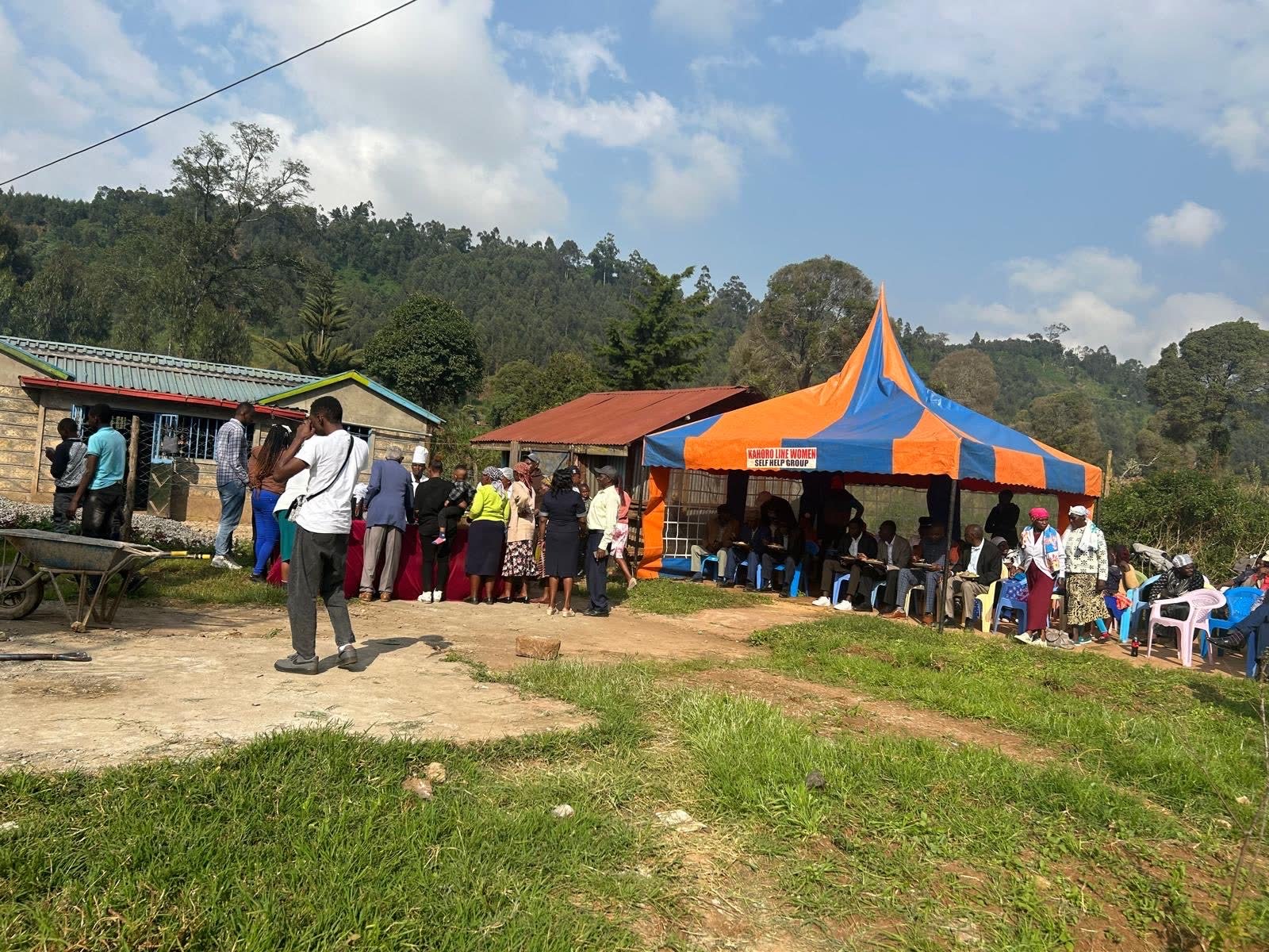 Community members gathered under a marquee tent for the well dedication