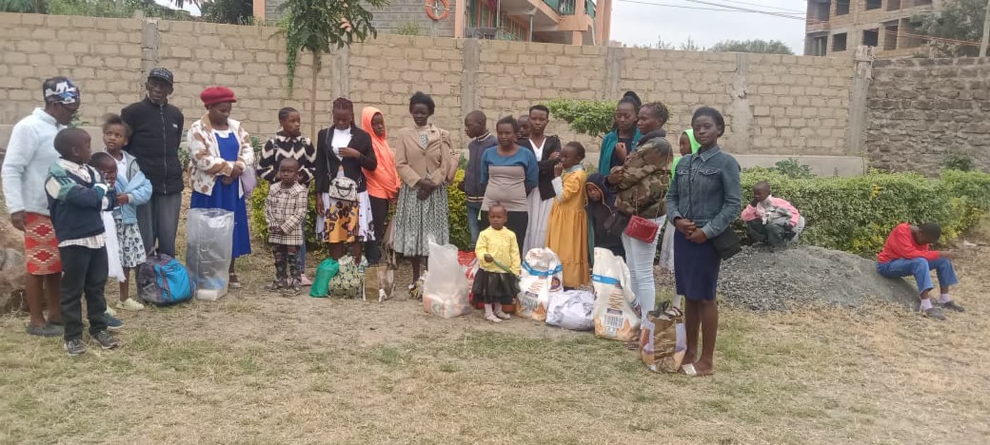 A group of families and children standing with bags of food they have received