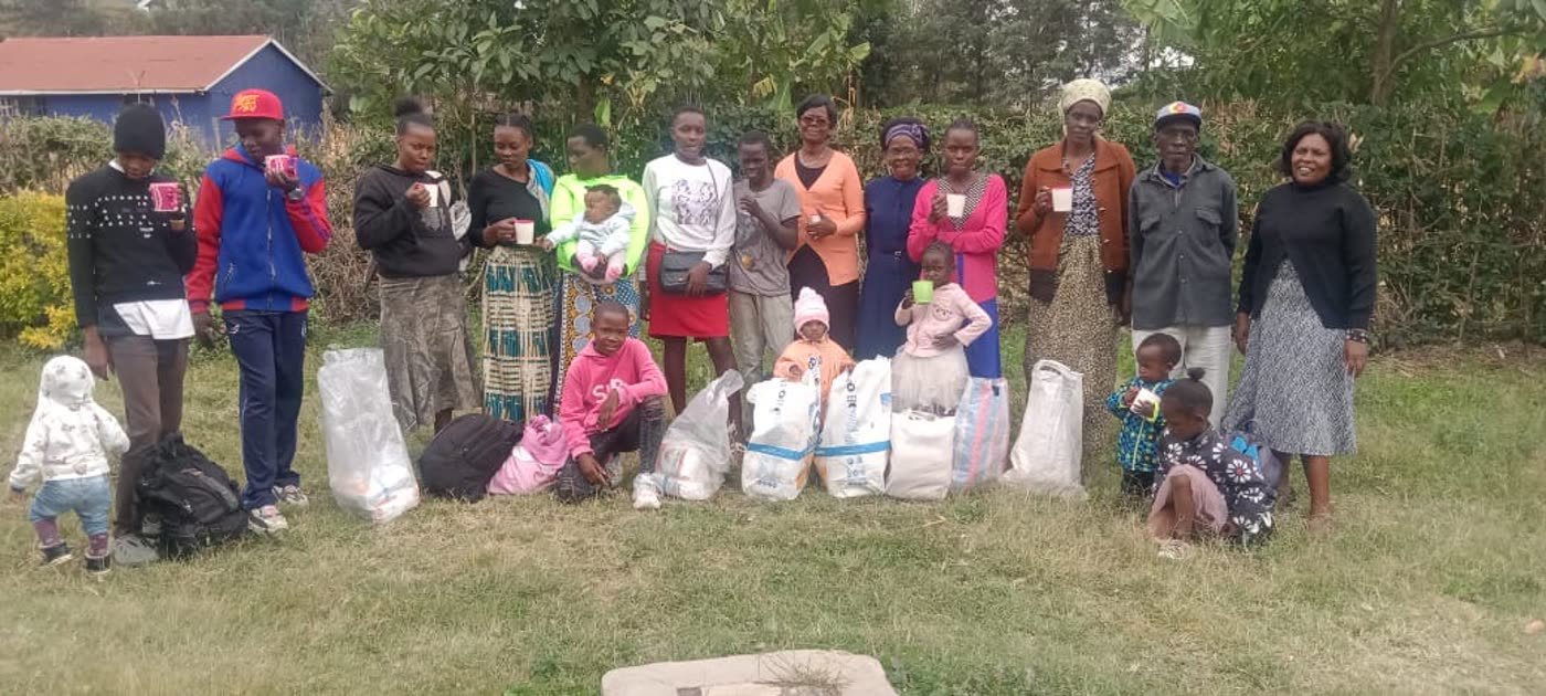 Families holding warm drinks beside the food parcels they have collected