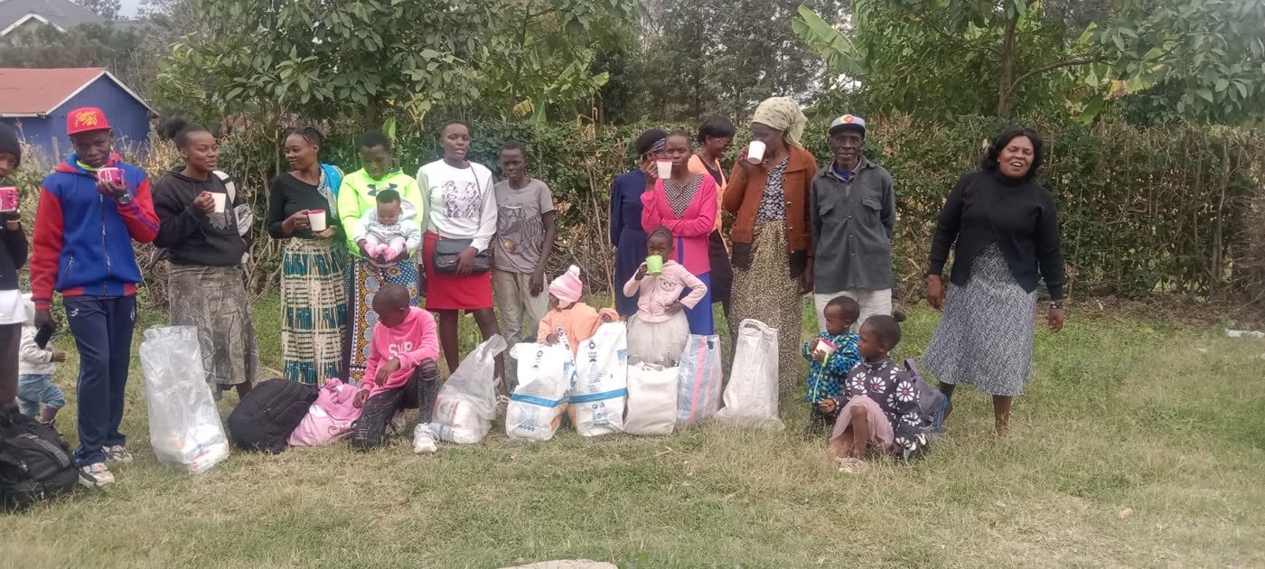 A line of families and children with sacks and bags of food on the grass