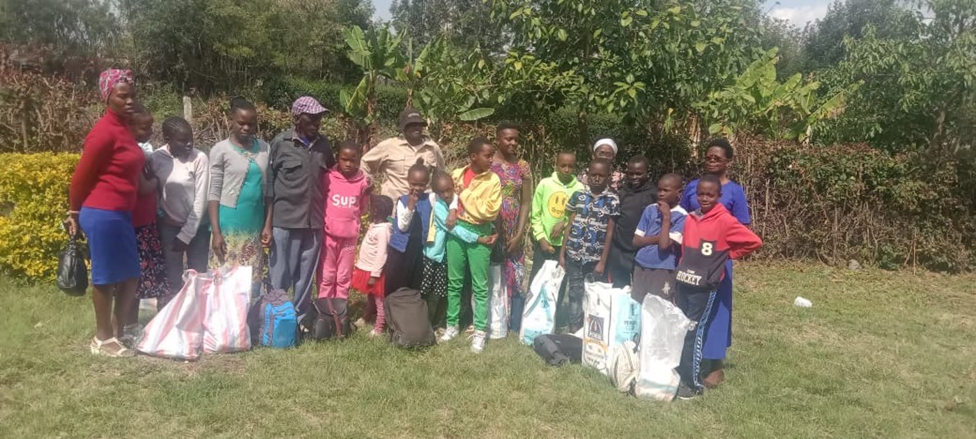 Children and parents gathered outdoors with bags of supplies