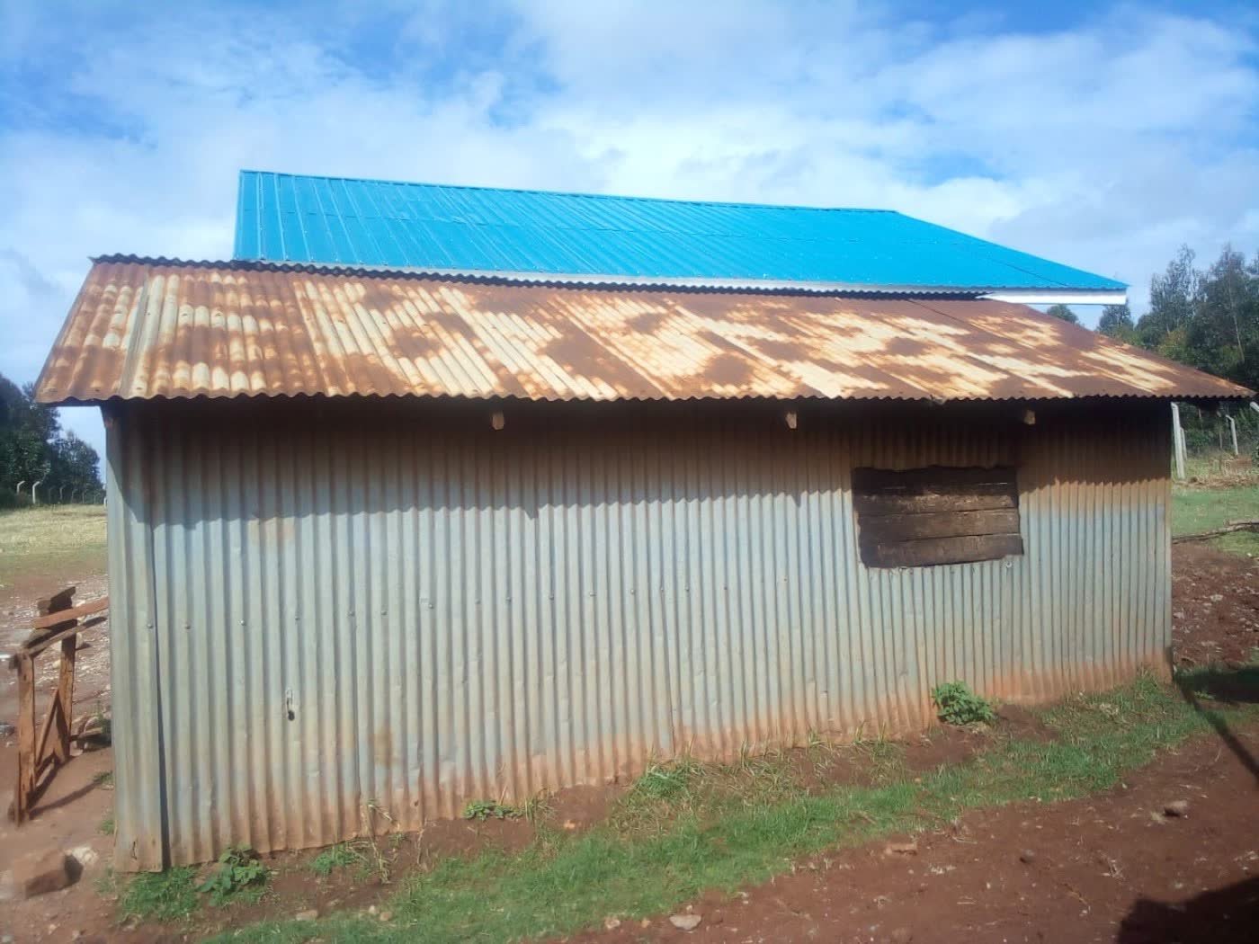The original school kitchen in Kenya: a small structure of rusted corrugated iron sheets with a wooden shuttered window