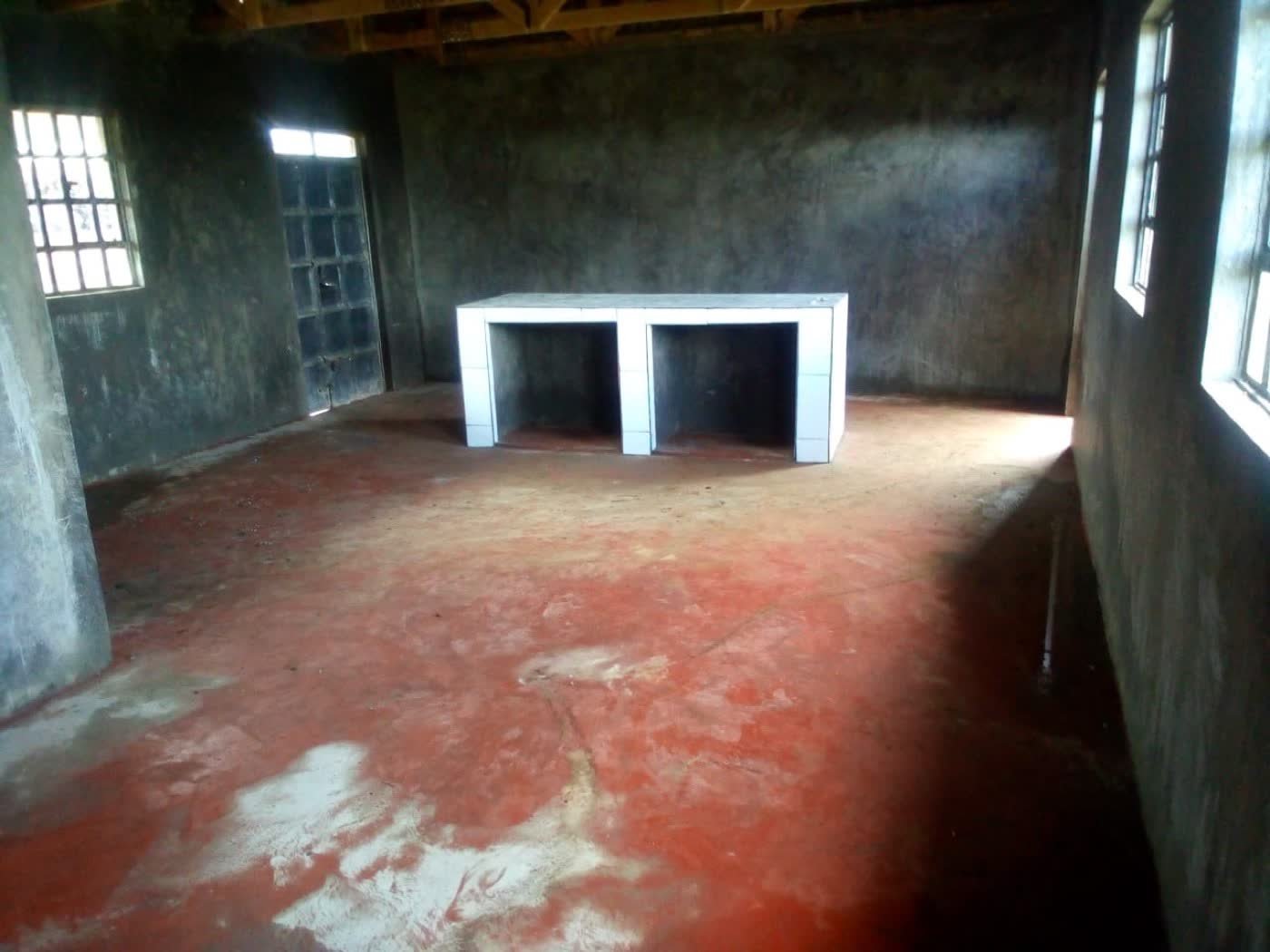 The interior of the new kitchen: plastered walls, a red-oxide floor, and a tiled serving counter