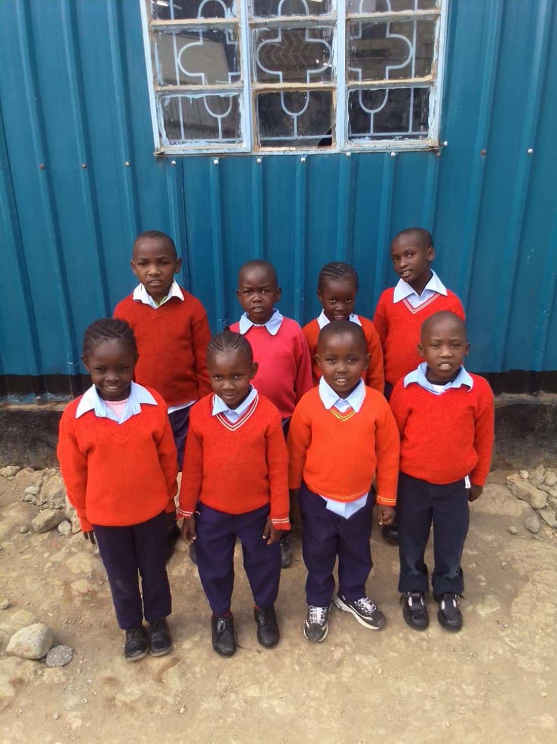 Pupils in red uniforms standing together outside their classroom