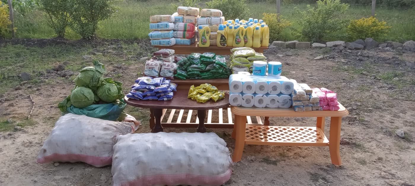 Maize flour, rice, cooking oil, cabbages, potatoes, soap and household supplies laid out on tables before a distribution